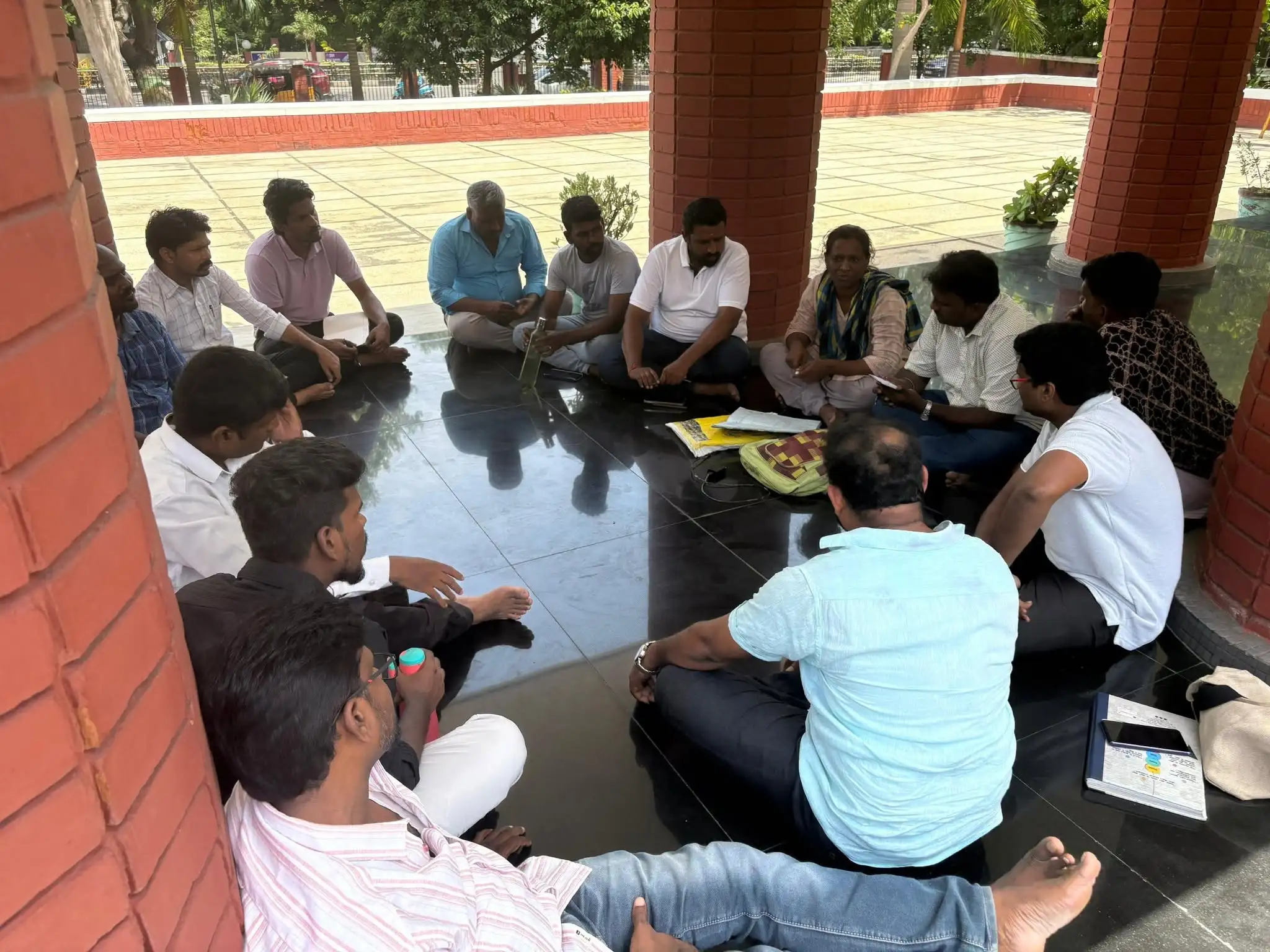 Members and supporters of Prabuddha Bharat Male Self Help Group seated in a circle during an outdoor meeting.